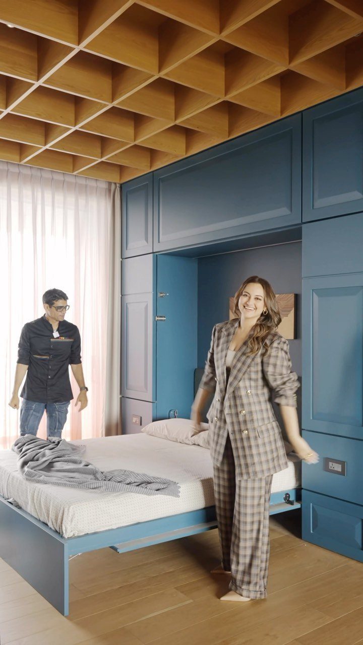 Woman standing by a blue pull-out bed in a small modern bedroom