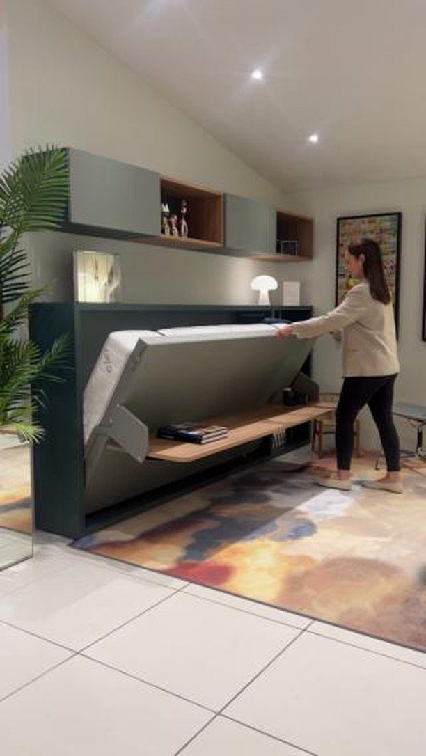 Woman pulling down a white mattress from a dark grey console bed unit.
