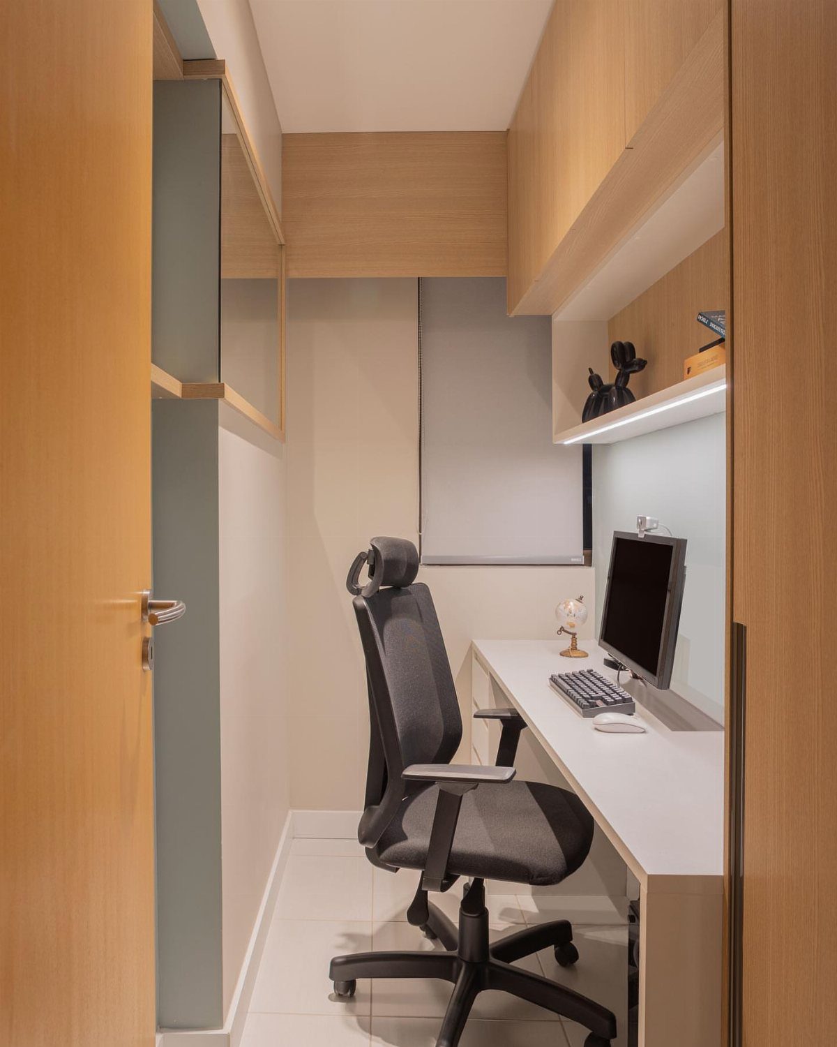 White desk and black office chair positioned next to an open wooden door.