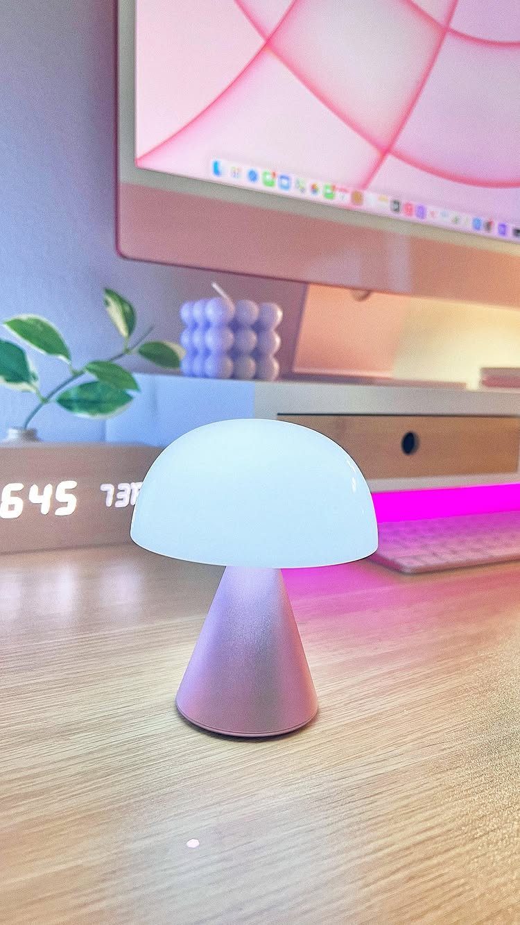 Mushroom-shaped desk lamp glowing on a light wood surface next to a monitor