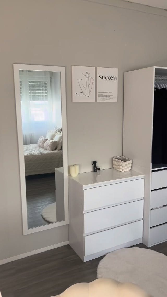 White dresser and full-length mirror in a minimalist small bedroom with beige walls.