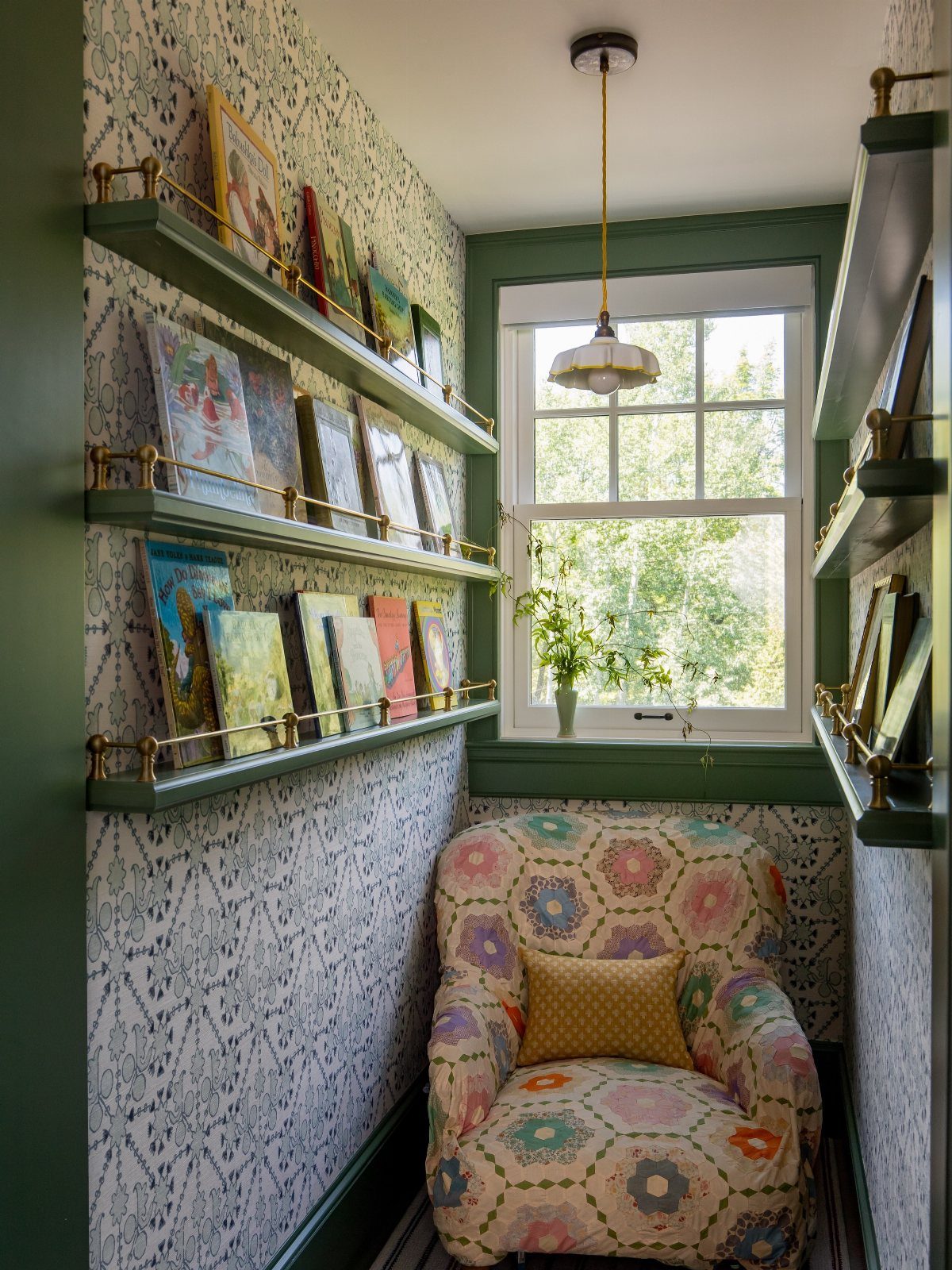 Narrow green picture ledges holding books and art on a patterned wall.