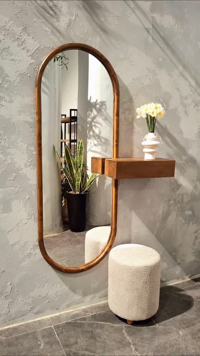 Oval wooden mirror with a small floating shelf and white bouclé stool.