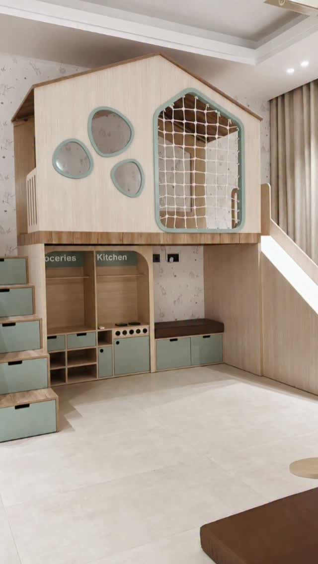 Wooden house-shaped loft bed with a play kitchen and storage underneath in a room.