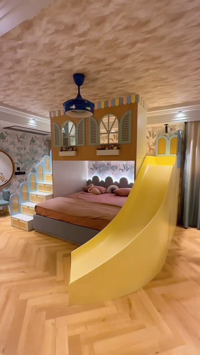 Children's loft bed with a yellow slide and house-themed upper level decorations.