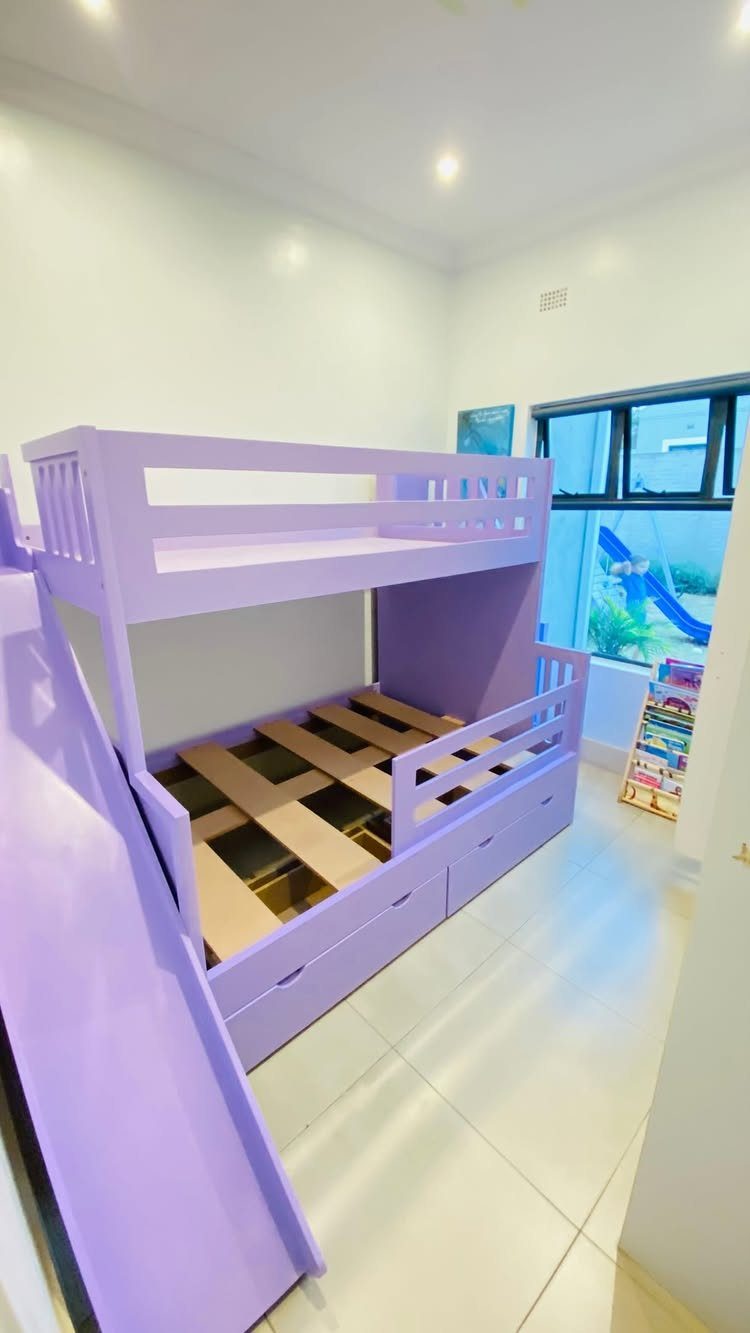 Purple bunk bed with built-in storage drawers and an attached slide in a bedroom.