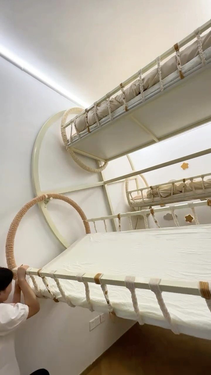 White metal bunk beds with circular frames and rope accents in a bright room.
