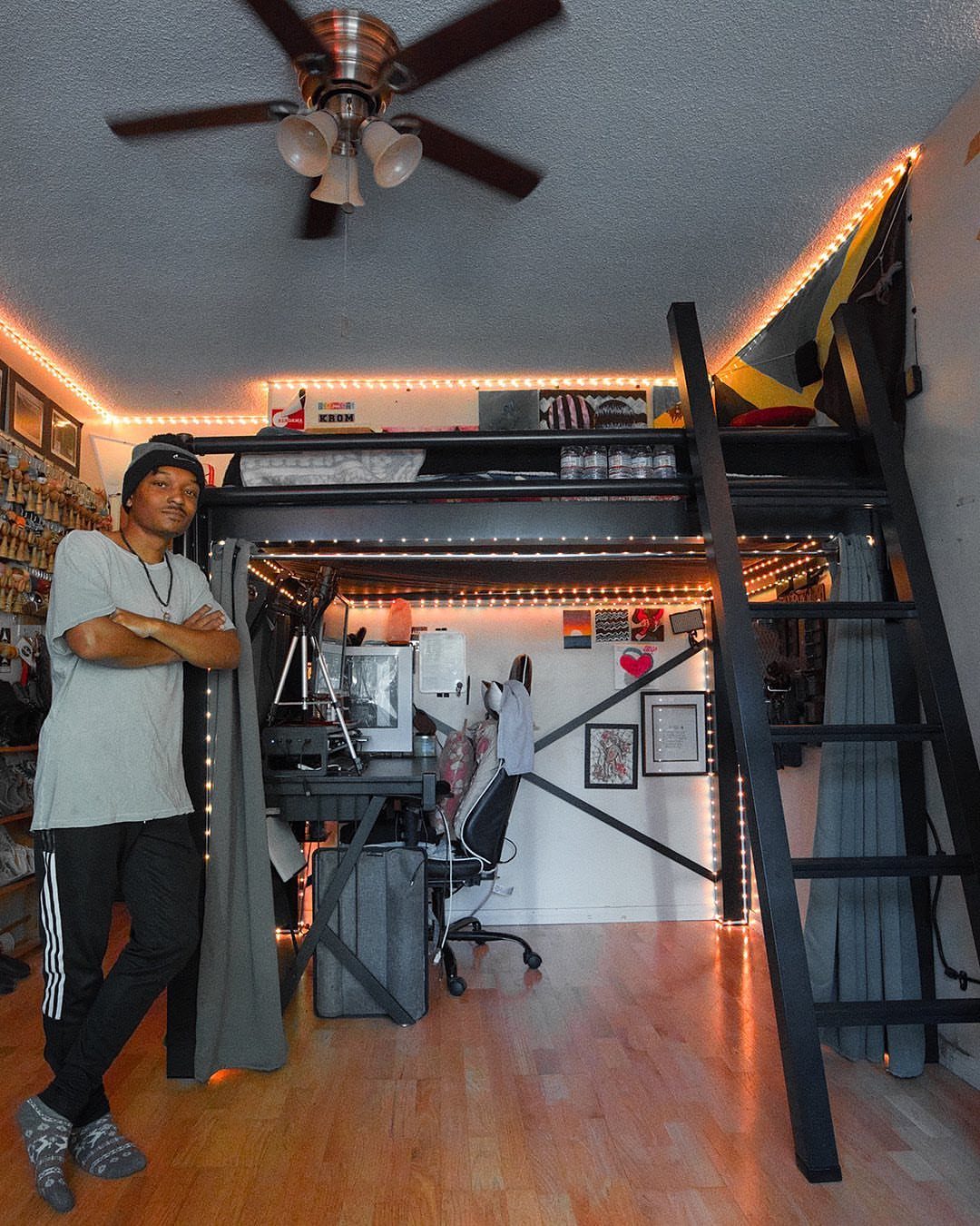 Black metal loft bed with a workspace and desk underneath in a bedroom.