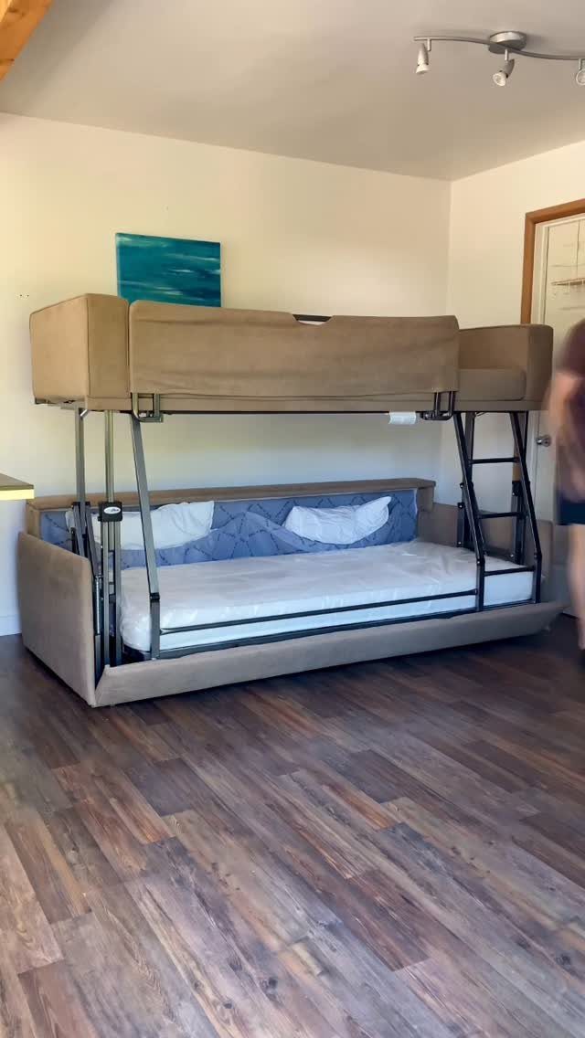 Bunk bed with tan fabric frame and wood flooring in a white room.