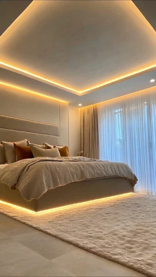 Modern bedroom with beige bedding and warm integrated LED strip lighting throughout.