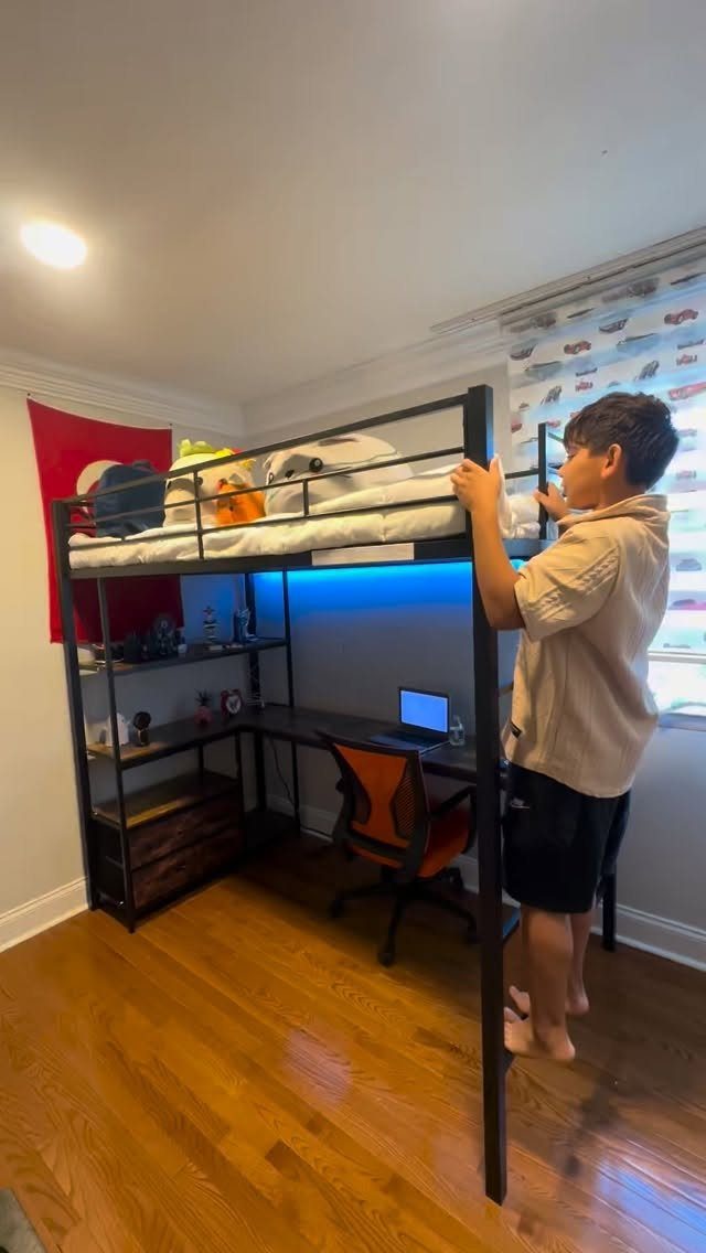 Black metal loft bed with a built-in study desk and orange chair underneath.