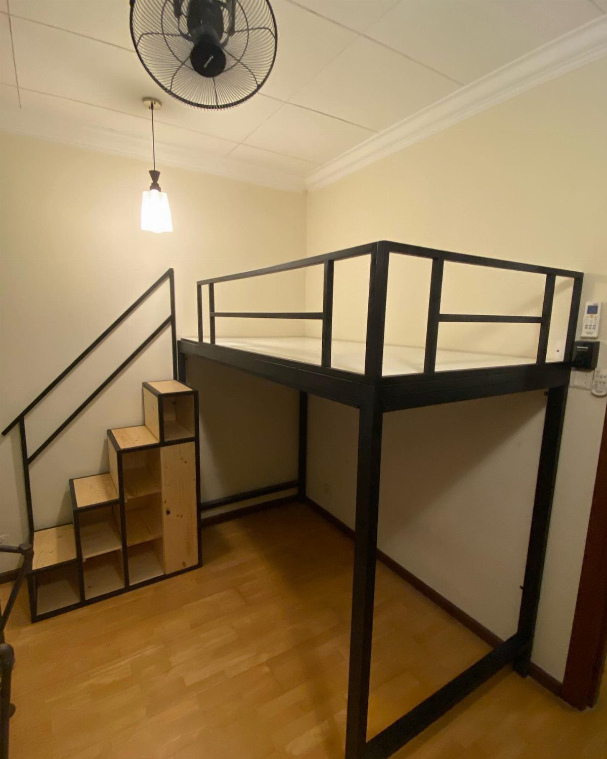 Black metal loft bed with wooden storage stairs in a beige bedroom