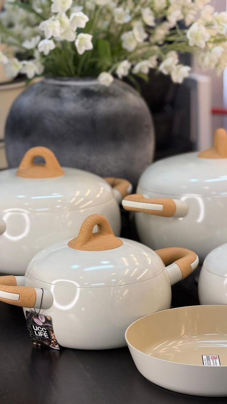 White ceramic pots with tan handles and lids next to a flower vase.