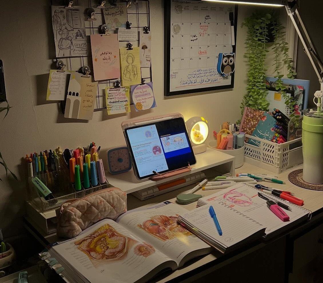 Study desk with anatomy textbook, tablet, colorful pens, and a desk lamp.