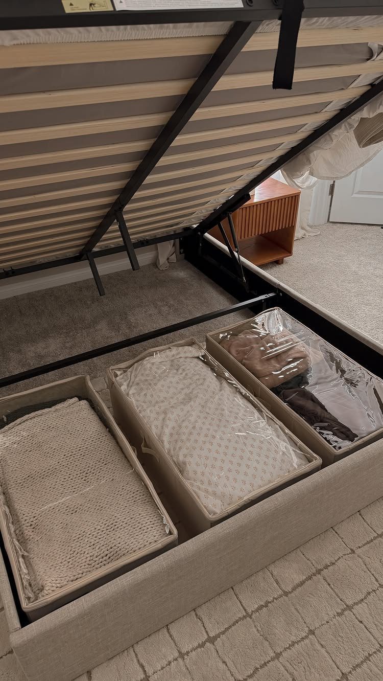 Fabric storage bins filled with linens tucked under a metal bed frame.