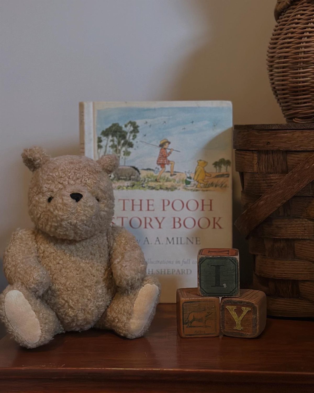 Winnie the Pooh plush toy sitting next to a storybook and wooden blocks.