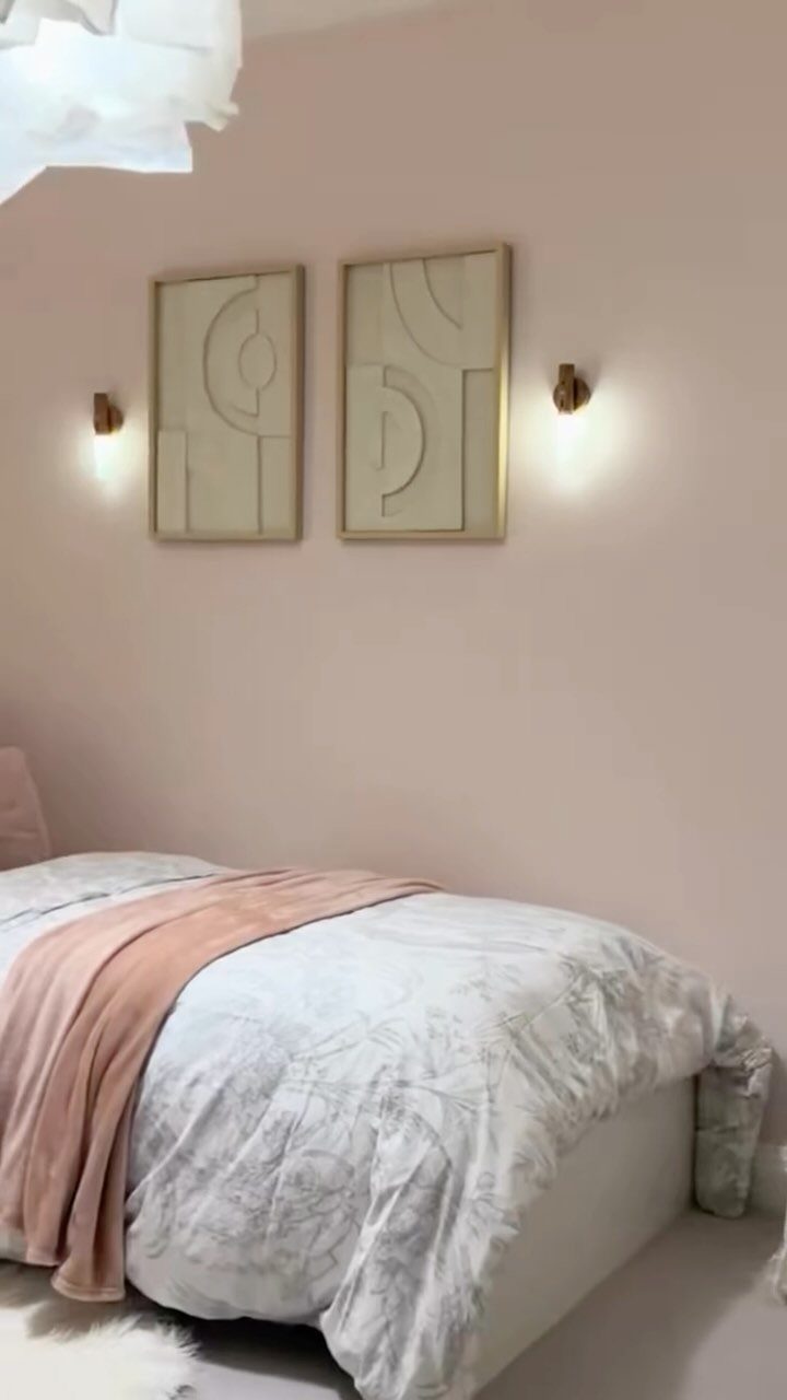 Blush pink bedroom walls with minimalist art and a bed with pink accents.