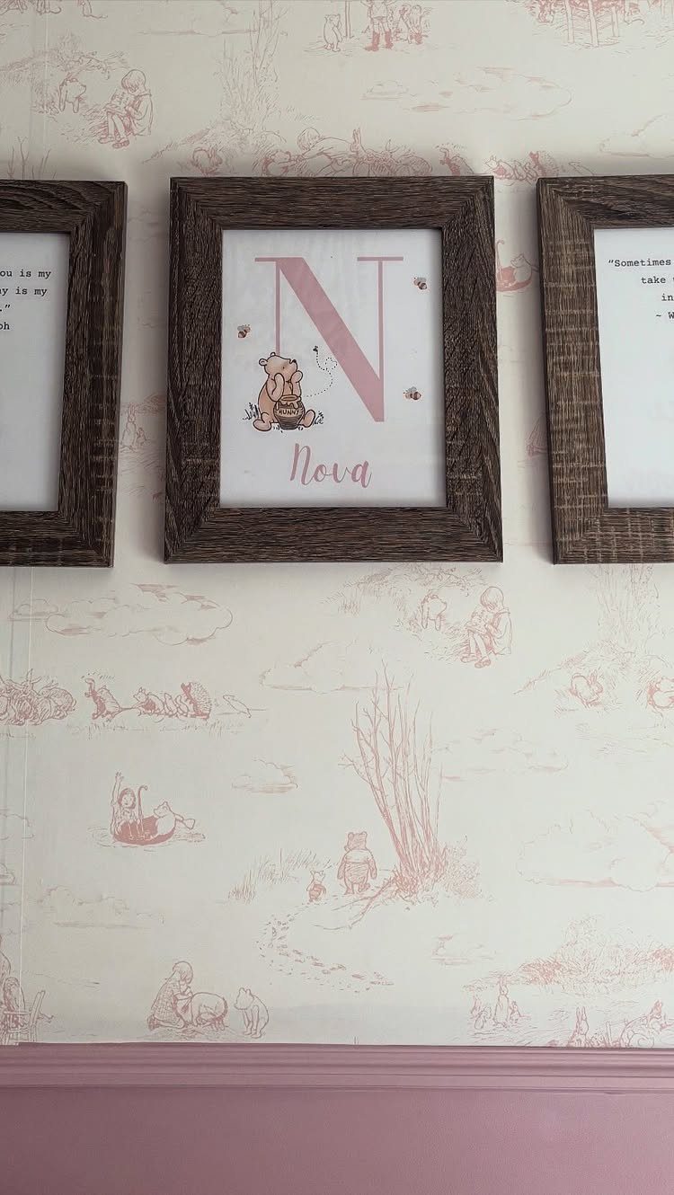 Winnie the Pooh themed nursery wall with framed name art and character wallpaper