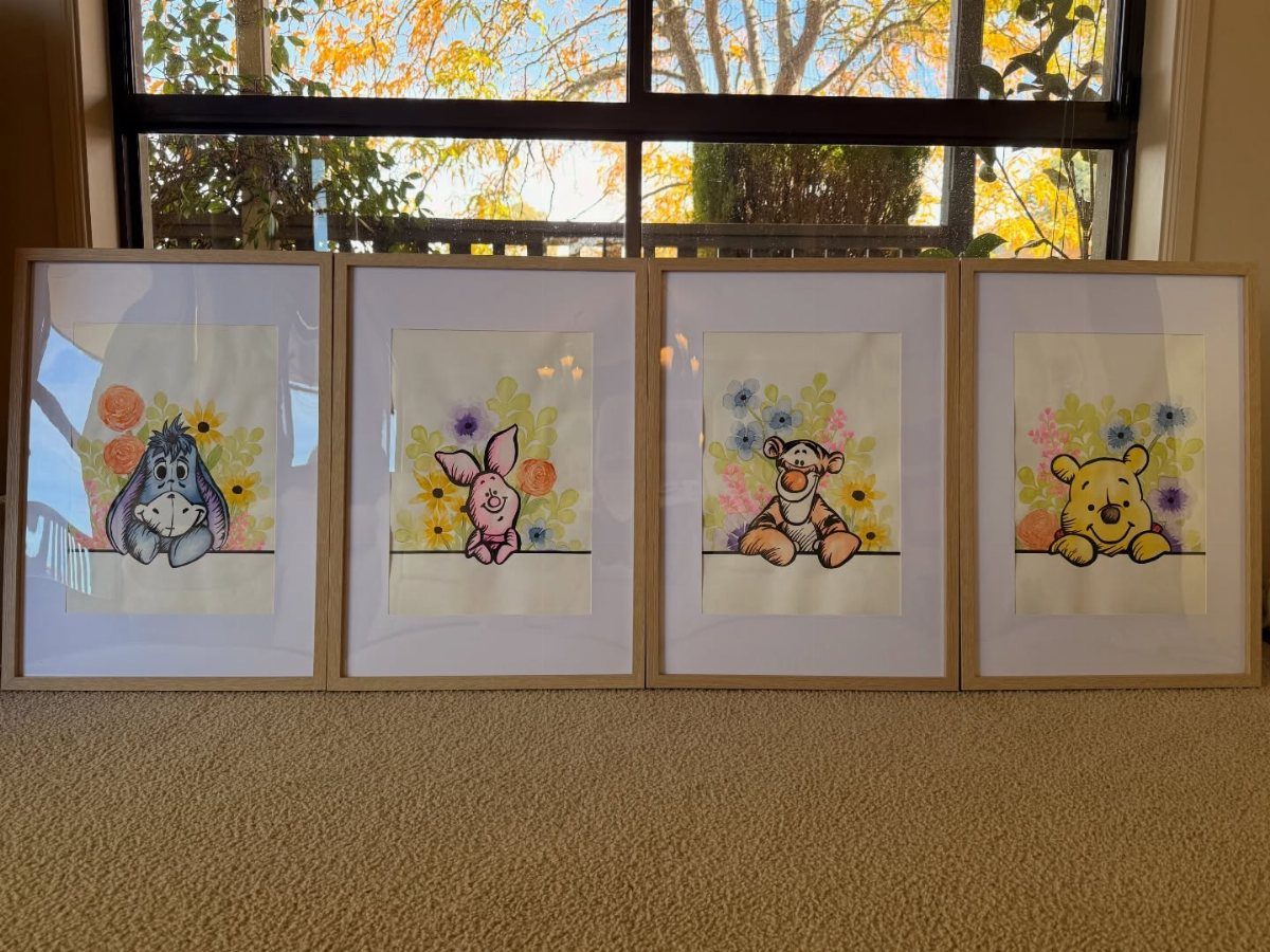 Four framed watercolor paintings of Winnie the Pooh characters leaning against a wall.
