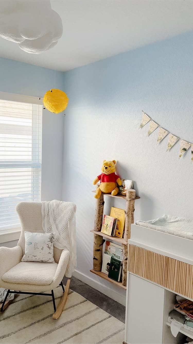 Winnie the Pooh themed nursery with blue walls, rustic shelving, and rocking chair.