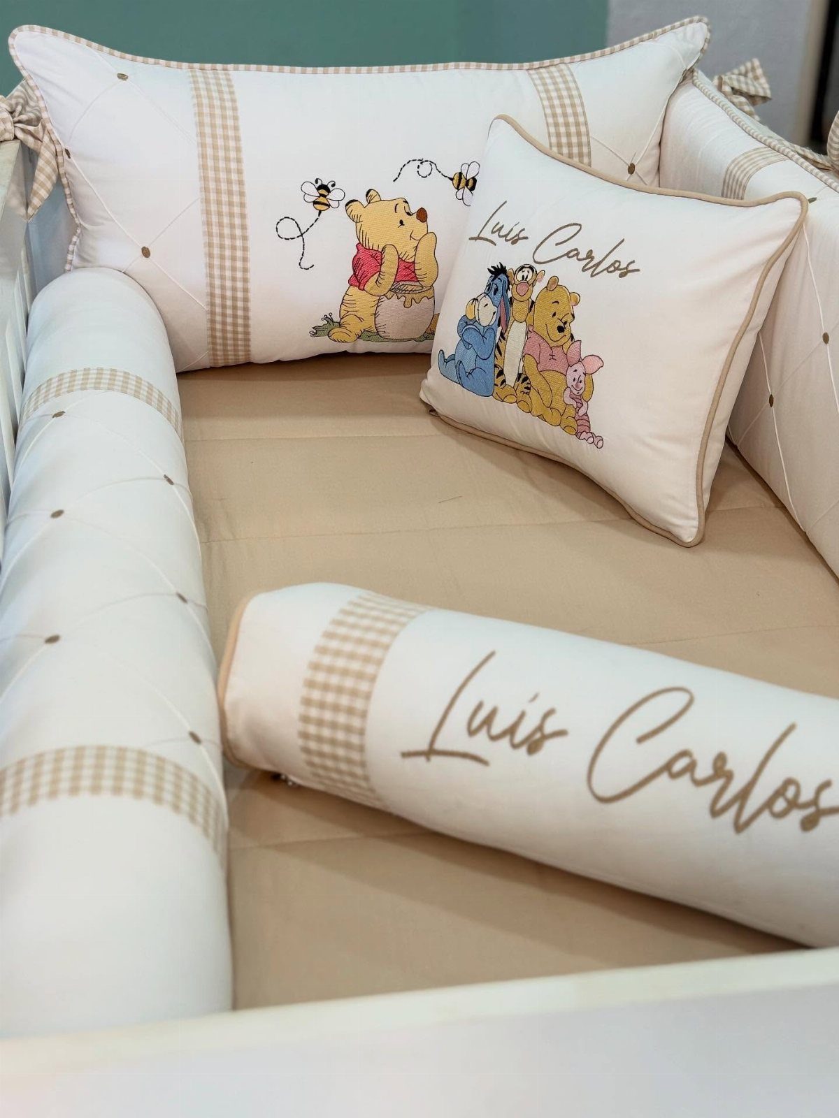Winnie the Pooh themed crib bedding with embroidered pillows and a name bolster.