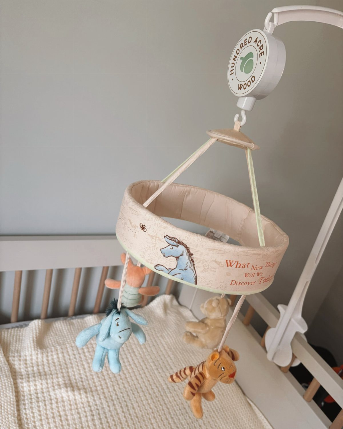 Winnie the Pooh baby mobile with plush characters hanging over a white crib